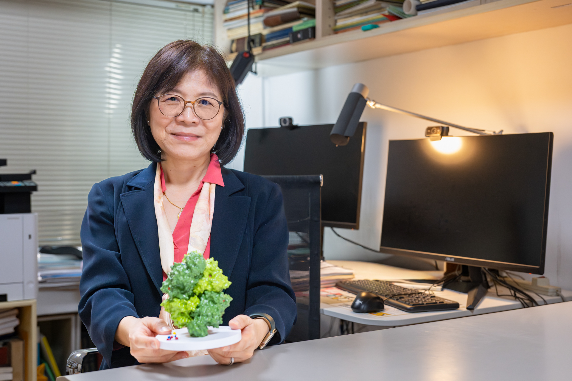 Professor Wen-Ching Wang presents a protein structure model from the study, highlighting the team's breakthrough in revealing how a critical 